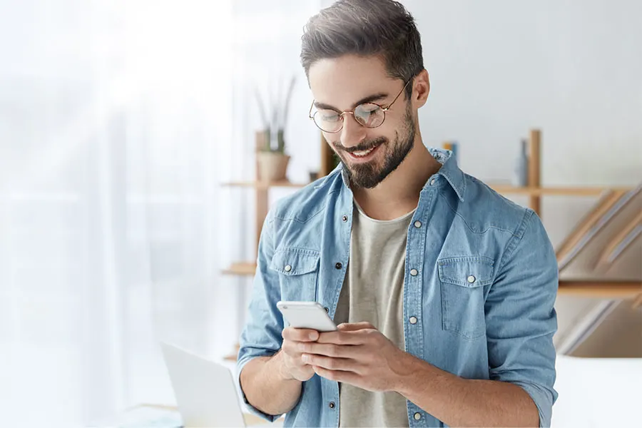 Man wearing glasses while looking at his phone