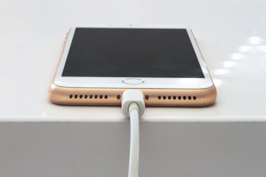 iphone connected to charger on top of table.