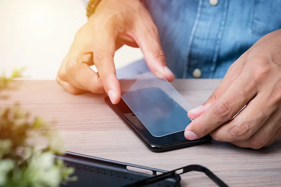 man placing glass screen protector on phone