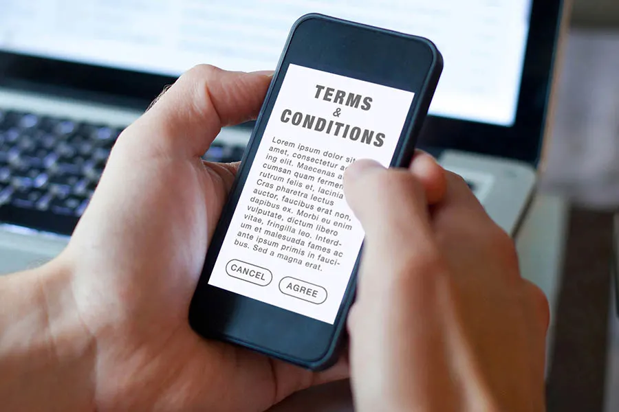 Person holding phone with terms and conditions on screen