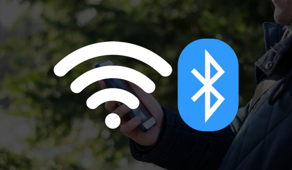 Man holding mobile phone in hand outdoors on a sunny day with Bluetooth and WiFi icons