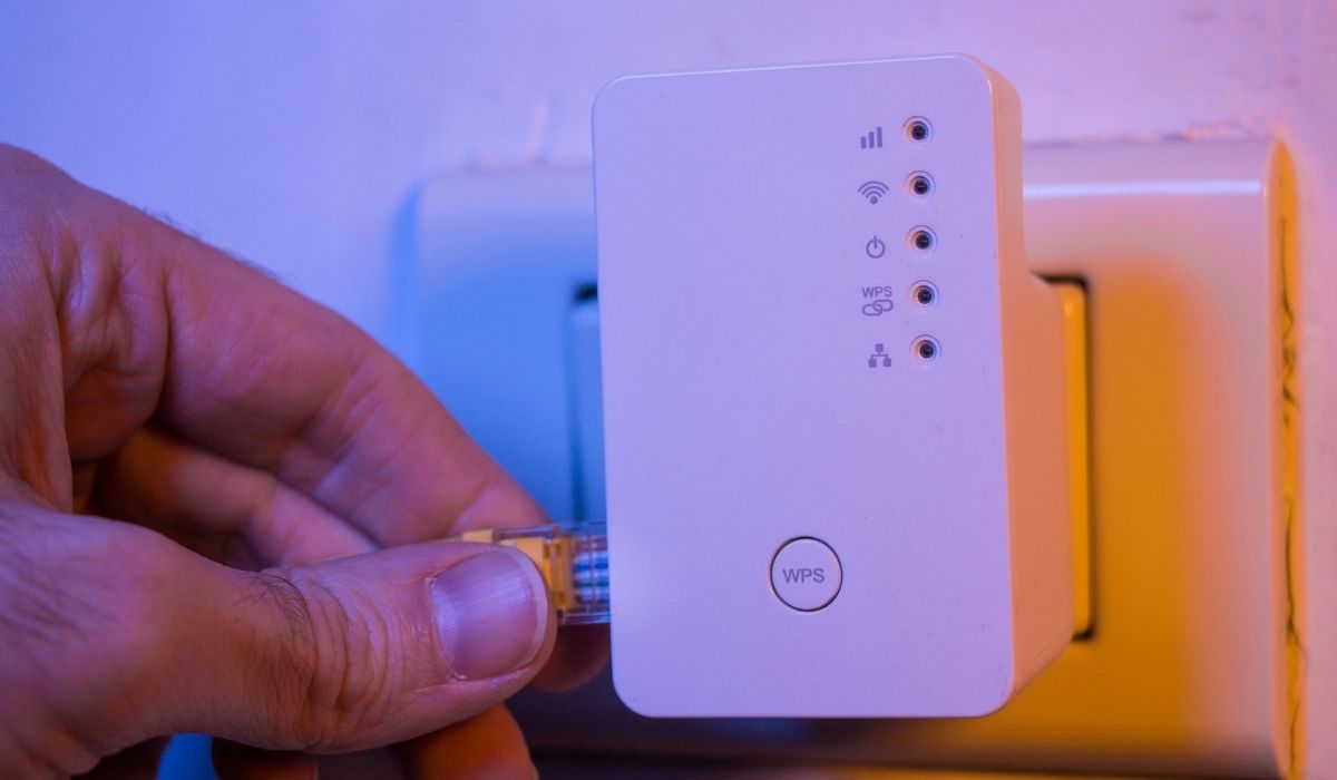 Man insert ethernet cable into WiFi extender device