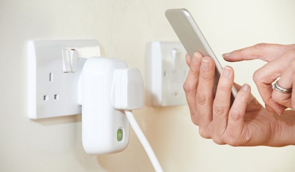 A Woman Controlling Smart Plug Using App On Mobile Phone