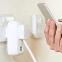 A Woman Controlling Smart Plug Using App On Mobile Phone