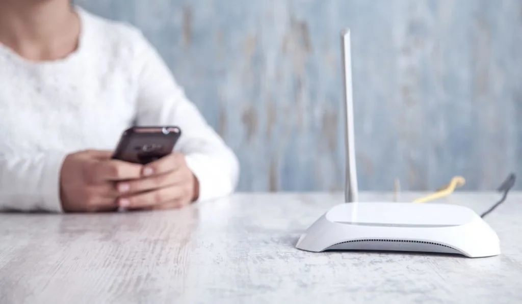 Internet router in the desk. Girl using smartphone