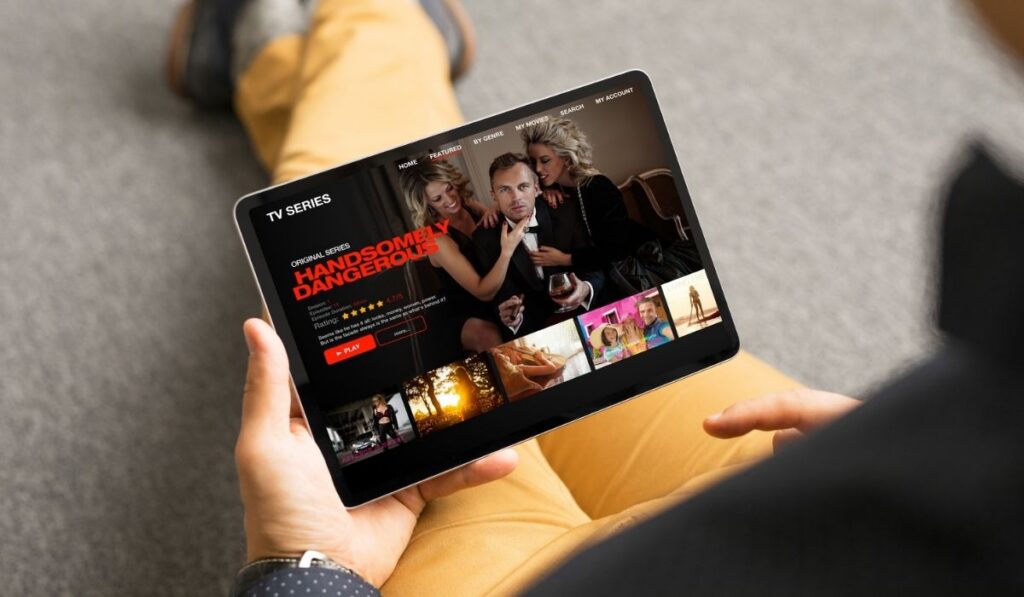 Man looking TV series and movies via streaming service on tablet