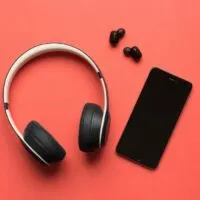 Stock photo of a bluetooth headphones and a smartphone on a red background