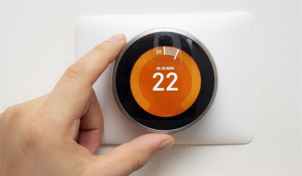 Smart Thermostat with a person warming up the room temperature with a soft shadow 