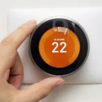 Smart Thermostat with a person warming up the room temperature with a soft shadow