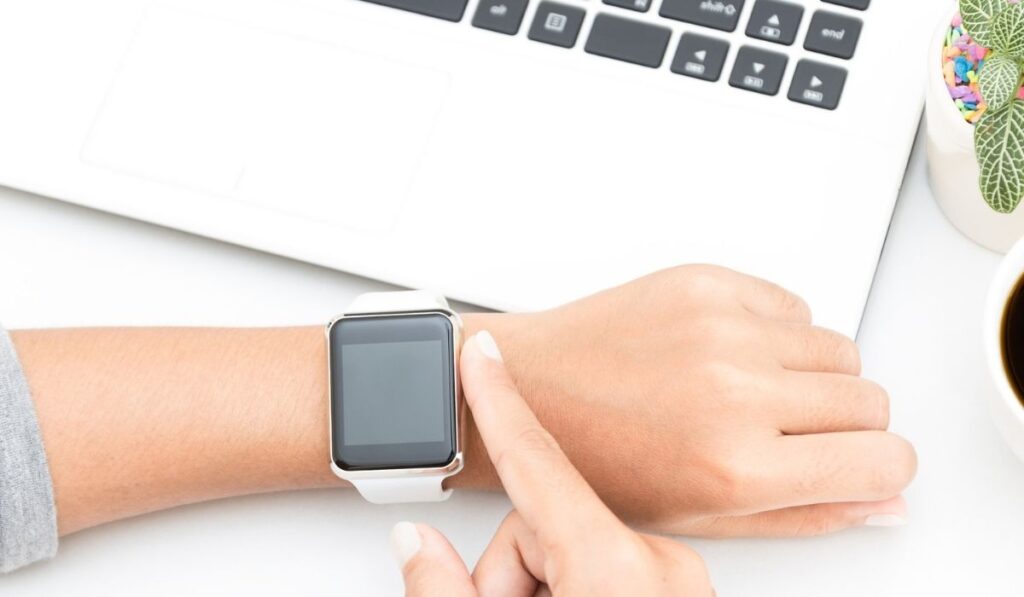 Woman touching smart watch hand on work table 