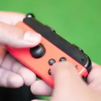 Closed up of guy`s hands playing on the red game console. a wireless console controller