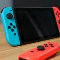Nintendo Switch, 2 joycons, and controller on a wooden desk - 2