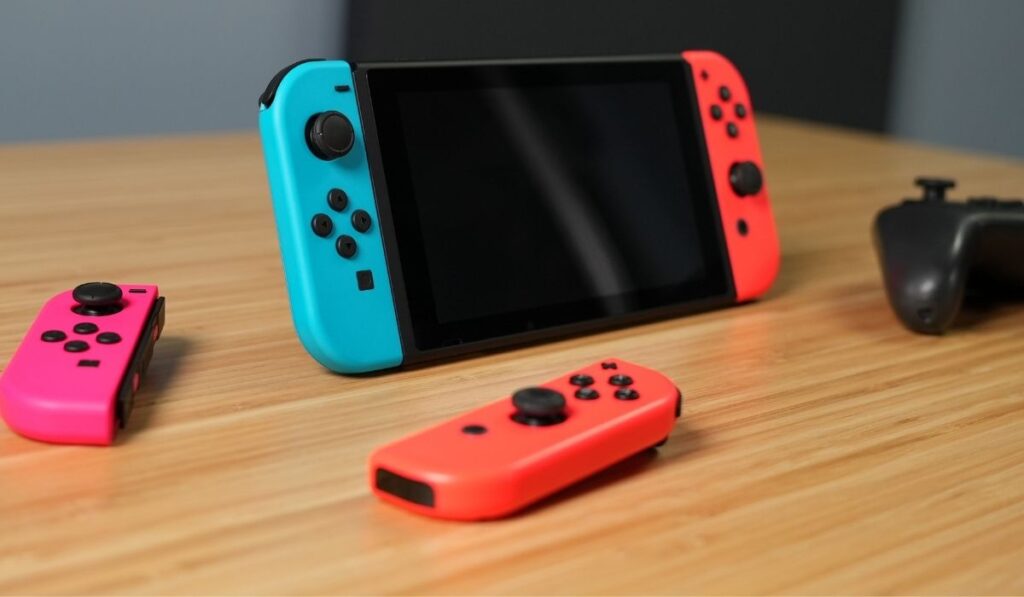Nintendo Switch, 2 joycons, and controller on a wooden desk - 3 