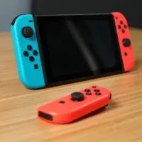 Nintendo Switch, 2 joycons, and controller on a wooden desk - 3