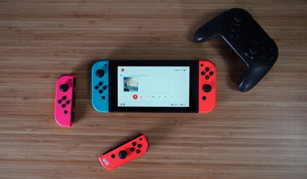 Nintendo Switch, 2 joycons, and controller on a wooden desk - 4