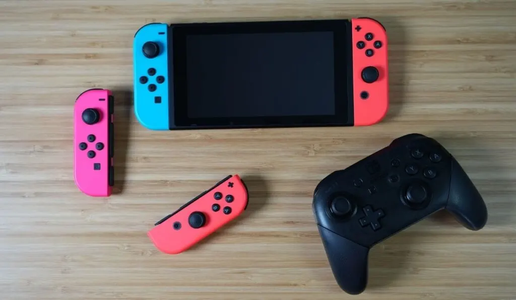 Nintendo Switch, 2 joycons, and controller on a wooden desk - 5