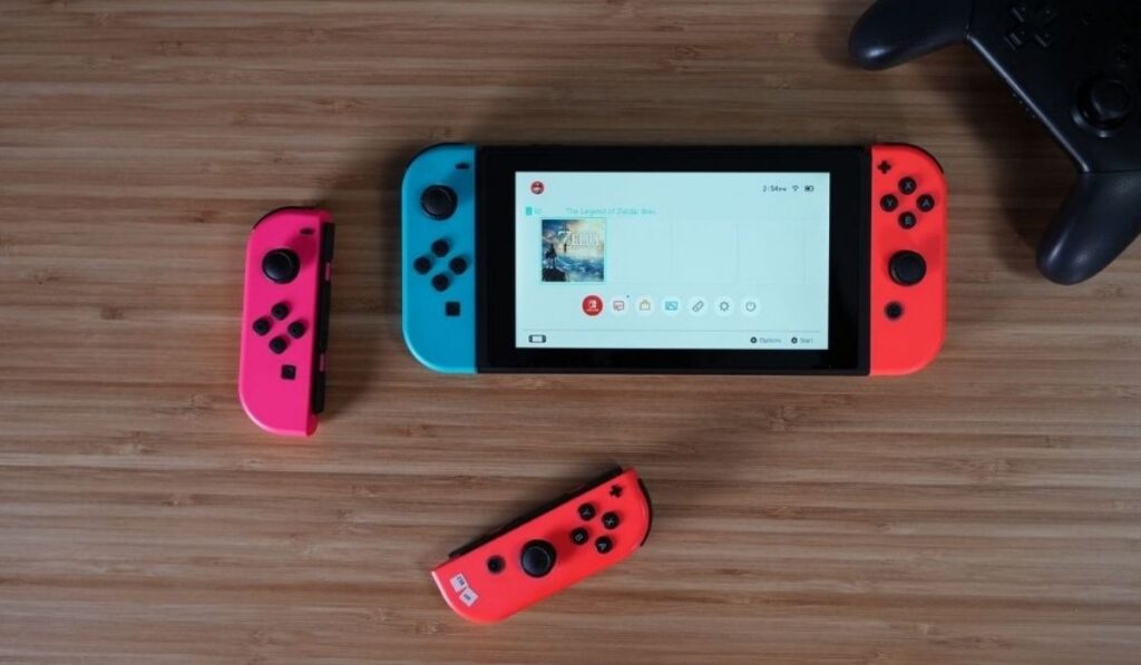 Nintendo Switch, 2 джойкона и контроллер на деревянном столе.
