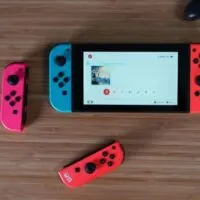 Nintendo Switch, 2 joycons, and controller on a wooden desk