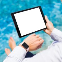 Woman using modern technology gadgets on vacation by the pool