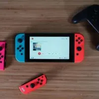 Nintendo Switch, 2 joycons, and controller on a wooden desk - 4