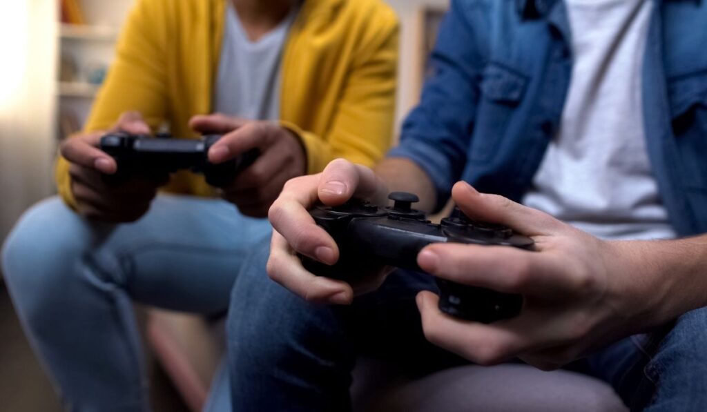 Два мультиэтнических подростка играют дома в компьютерные игры