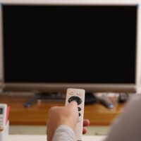 A women hand hold the remote control of the TV box in the living room