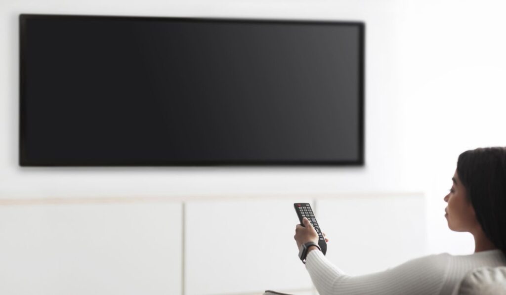 Black lady watching television, turning on plasma flatscreen TV-set 