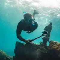 Freediver shooting on gopro coral reef with fish near wreckship