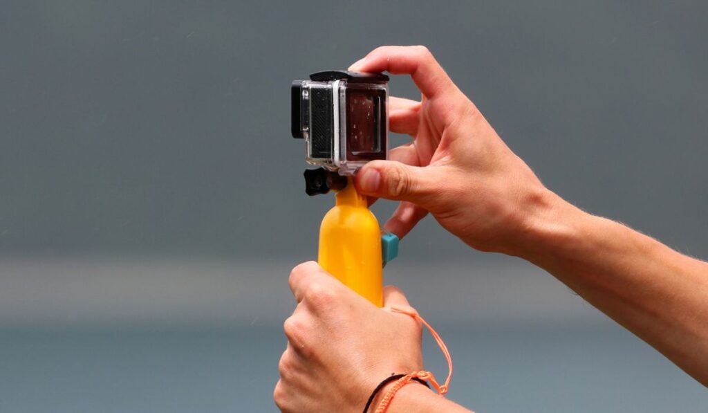Рука держит камеру GoPro с ручкой 