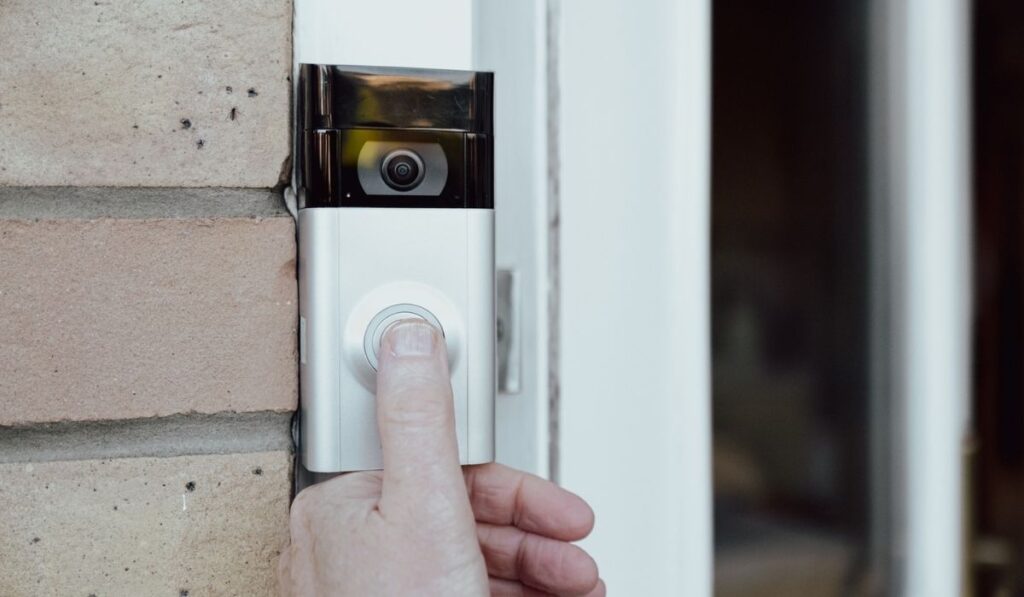 Shallow focus of a homeowner seen testing a newly installed WiFi smart doorbell 
