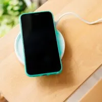Smartphone in mint silicone case is charged from a wireless charger