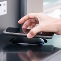 Woman hands charging battery in mobile smart phone by wireless charger