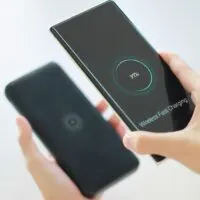 Woman holding smartphone using wireless charging technology