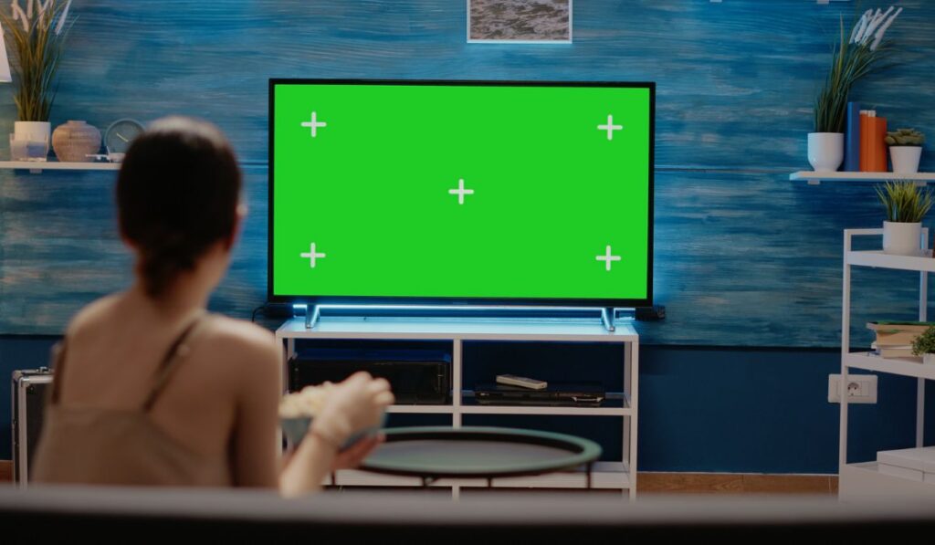 Woman looking at tv designed with green screen 