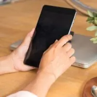 Beautiful business working woman using Ipad while working with laptop and reading report