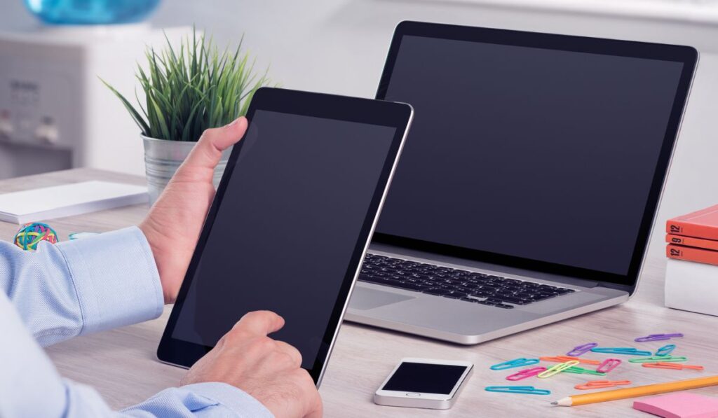 Businessman using ipad digital tablet pc and macbook laptop on the office desk