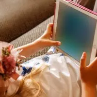 Cute girl kid using iPad digital computer tablet on bed for education or playing game
