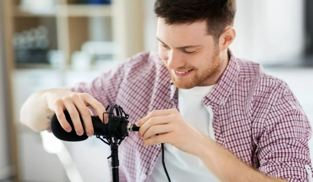 Male audio blogger connecting cable to microphone