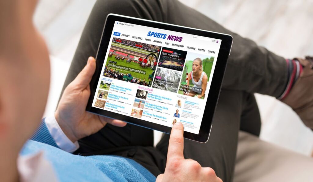 Мужчина читает спортивные новости на планшете 