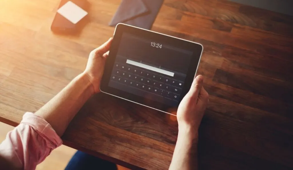Mans hands using a digital iPad tablet at office