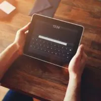 Mans hands using a digital iPad tablet at office