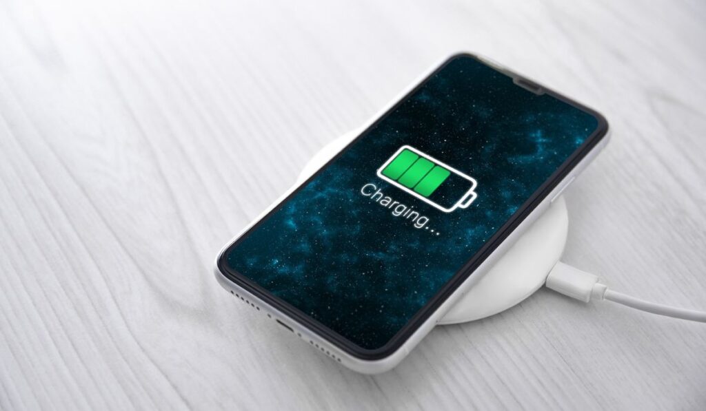 Mobile smart phone on wireless charging device on white background