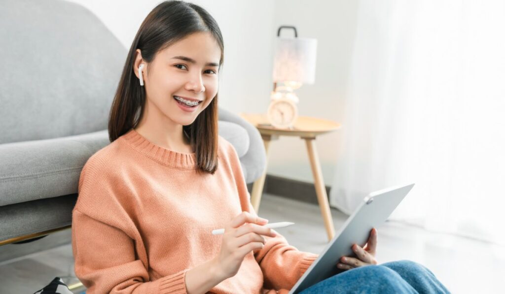 Young Asian woman using digital tablet and listen music to relaxing on the sofa at the house 