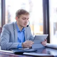 Young draftsman talking with client by tablet