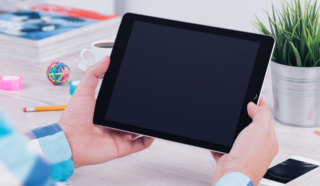 Young man holding ipad digital tablet on table desk