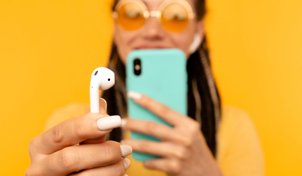 Closeup view of phone and airpods on the yellow background