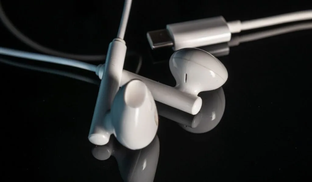 Earbuds or headsets with USB type-C connector with reflection on shiny black background