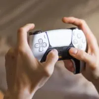 Holding Play Station 5 Dual Sense controller and playing video games at home