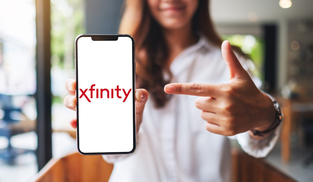 Женщина держит телефон с Xfinity на нем