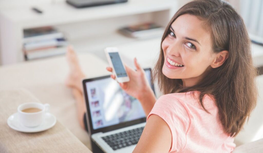 Busy woman at home using mobile phone and laptop at the same time -